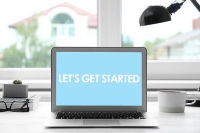 Image of Modern laptop with phrase Let's Get Started on screen in office