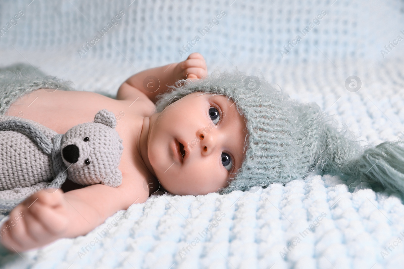 Photo of Cute newborn baby with crochet toy on light blue blanket