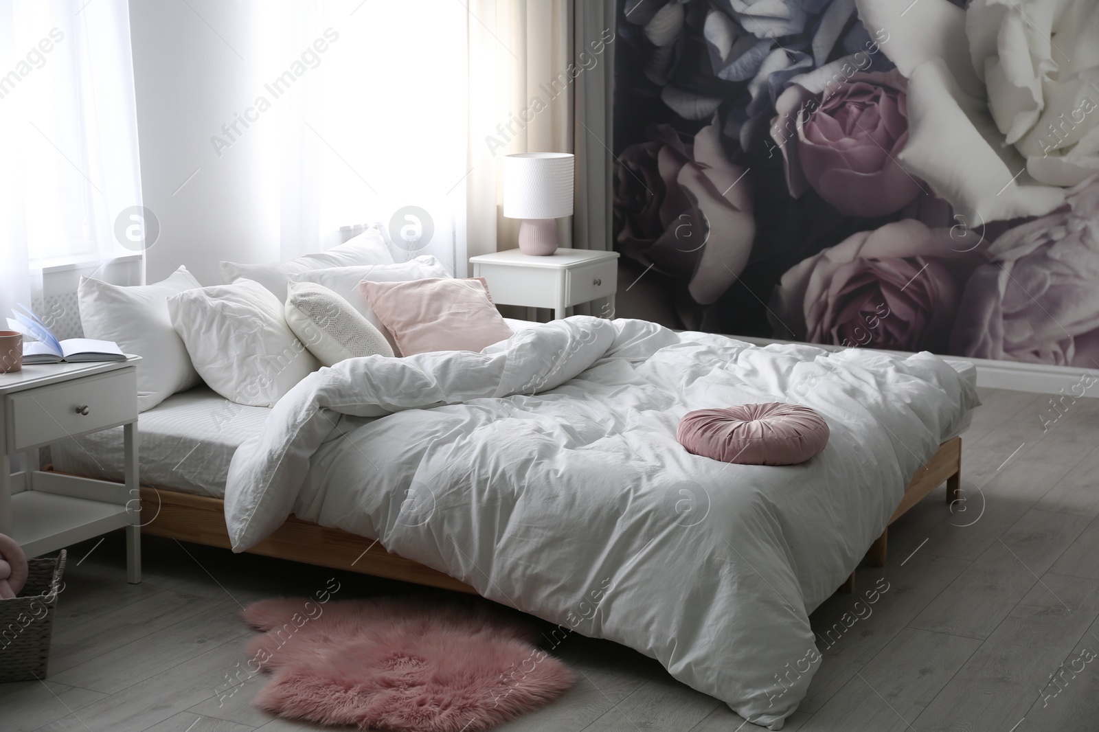 Photo of Comfortable bed near wall with floral wallpaper. Stylish room interior