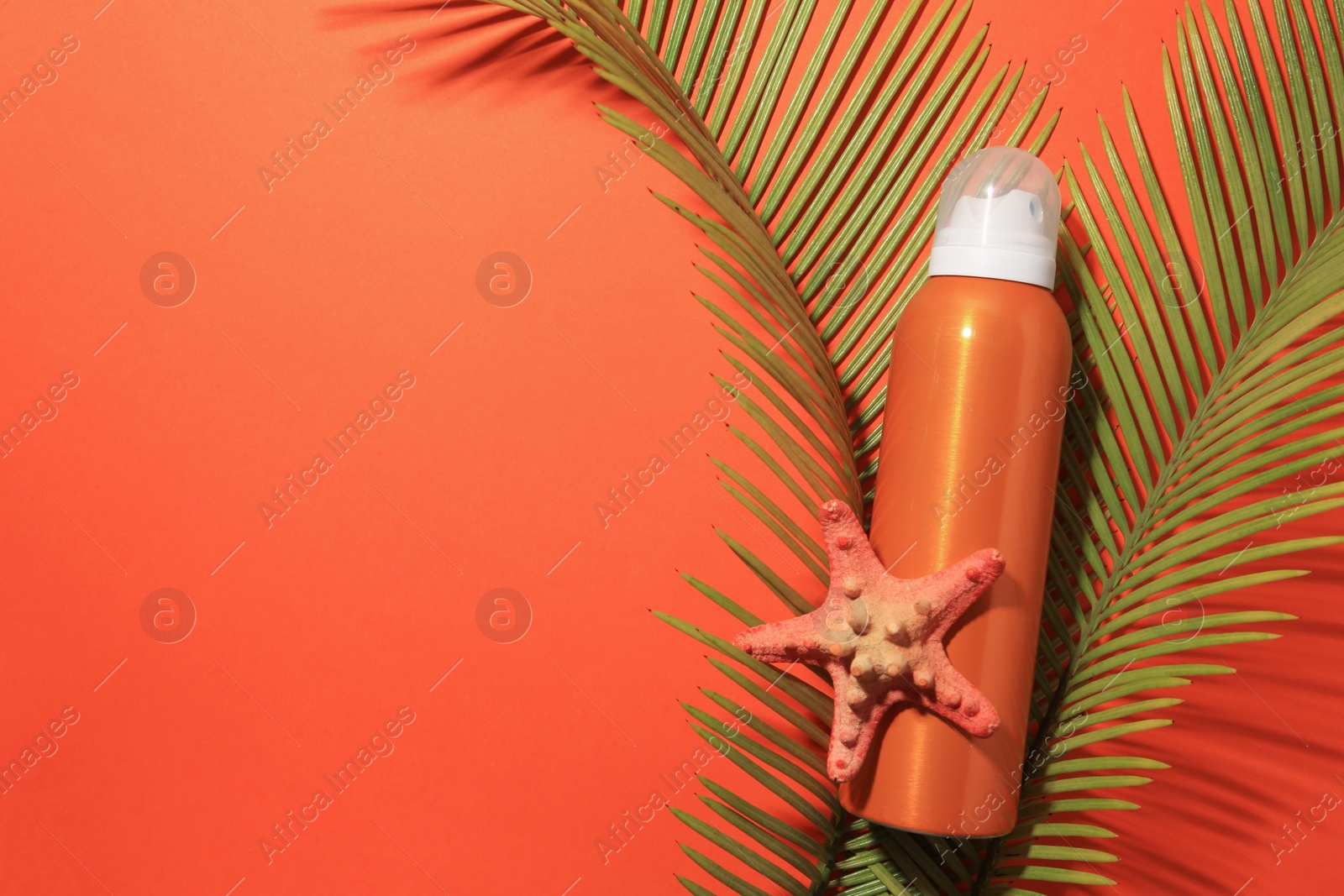 Photo of Sunscreen, starfish and tropical leaves on coral background, flat lay and space for text. Sun protection care
