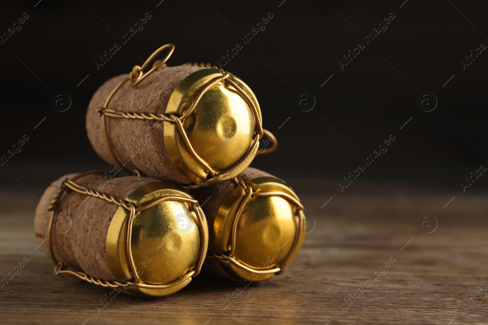 Photo of Corks of sparkling wine and muselet caps on wooden table, closeup. Space for text