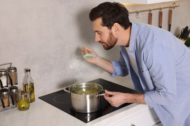 Man cooking delicious chicken soup in kitchen