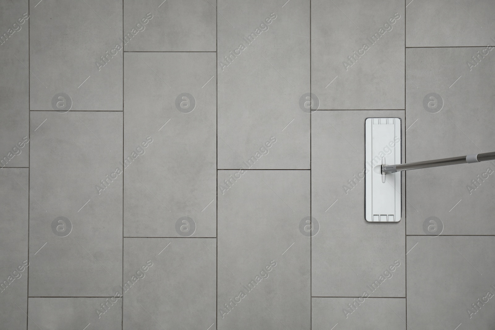 Photo of Cleaning grey tiled floor with mop, top view. Space for text