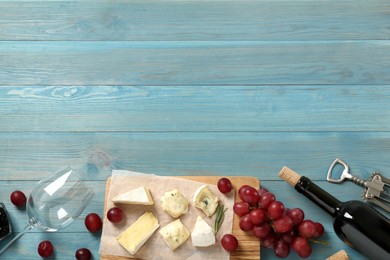 Flat lay composition with red wine and snacks on turquoise wooden table, space for text