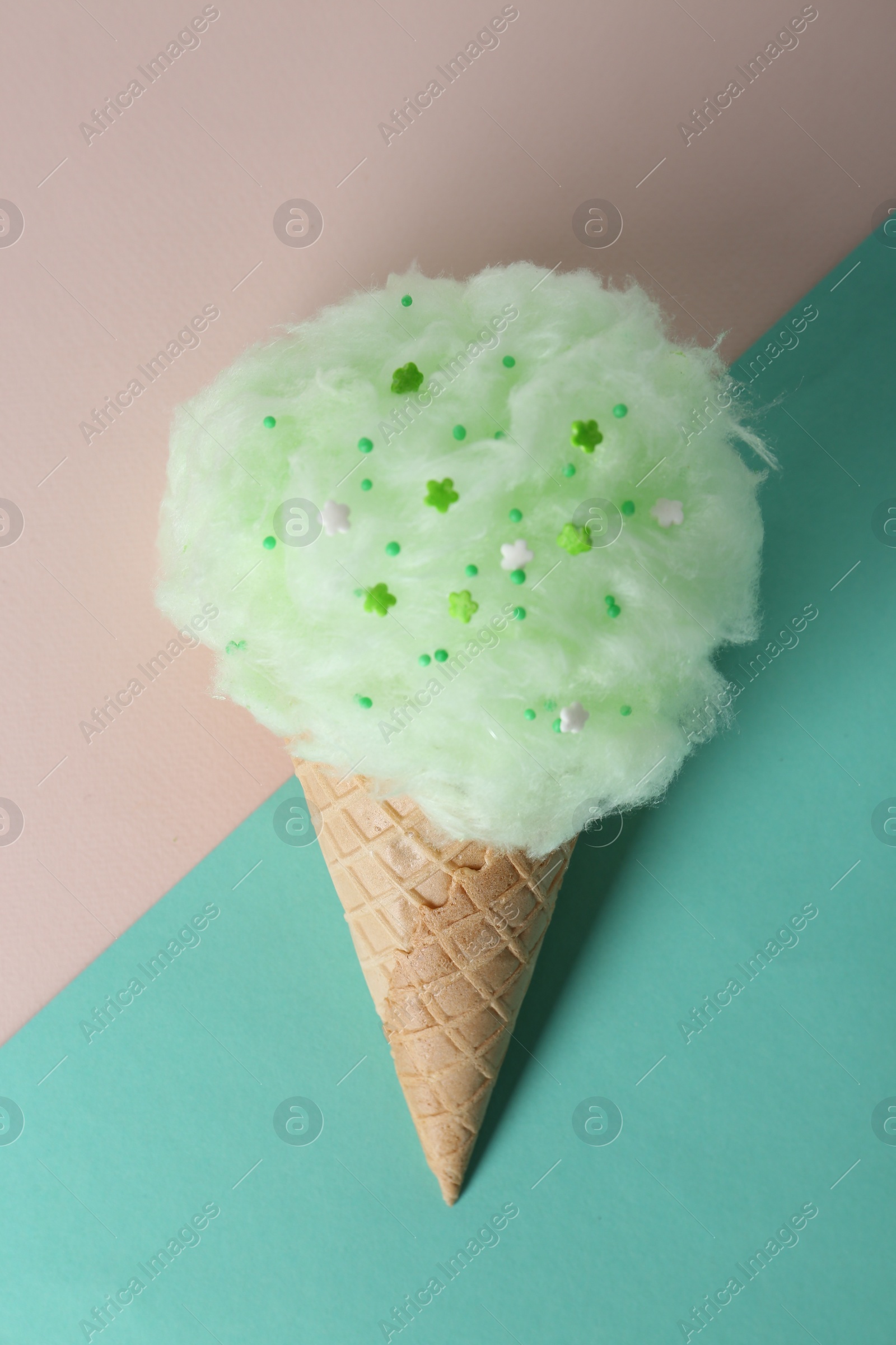 Photo of Sweet cotton candy in waffle cone on color background, top view