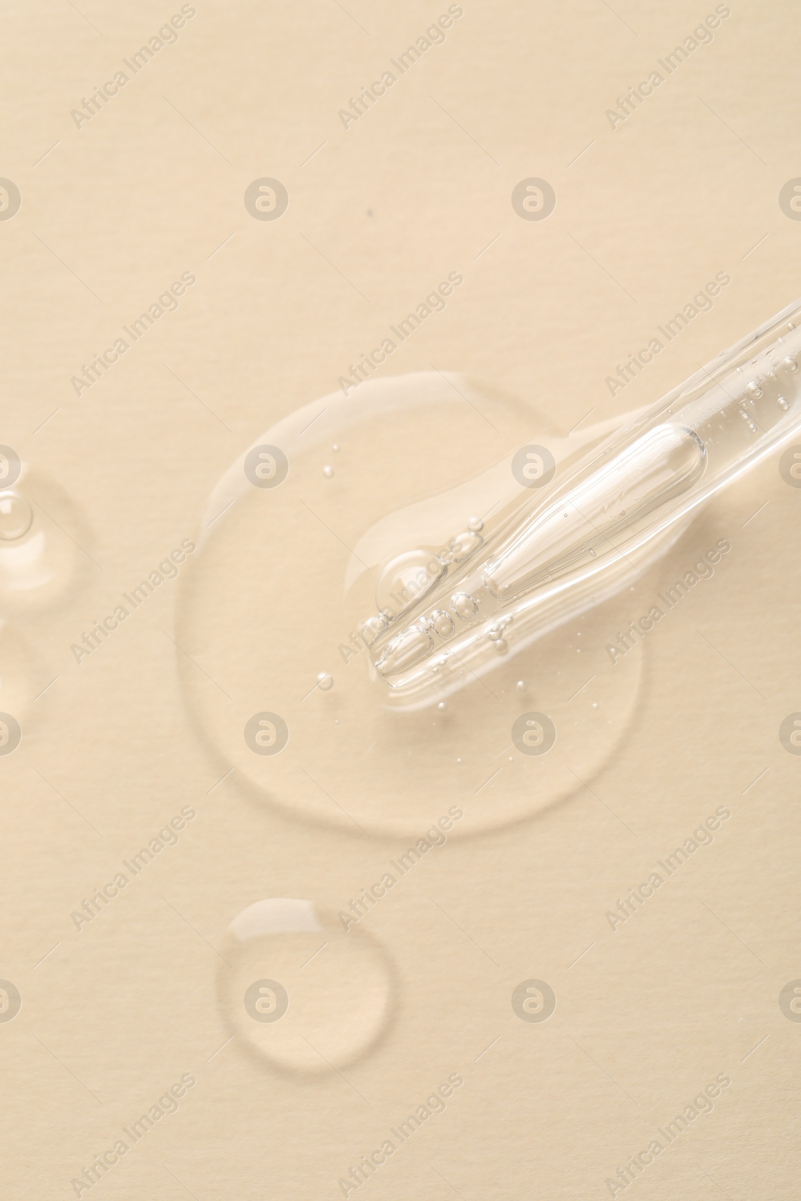 Photo of Glass pipette and transparent liquid on beige background, top view