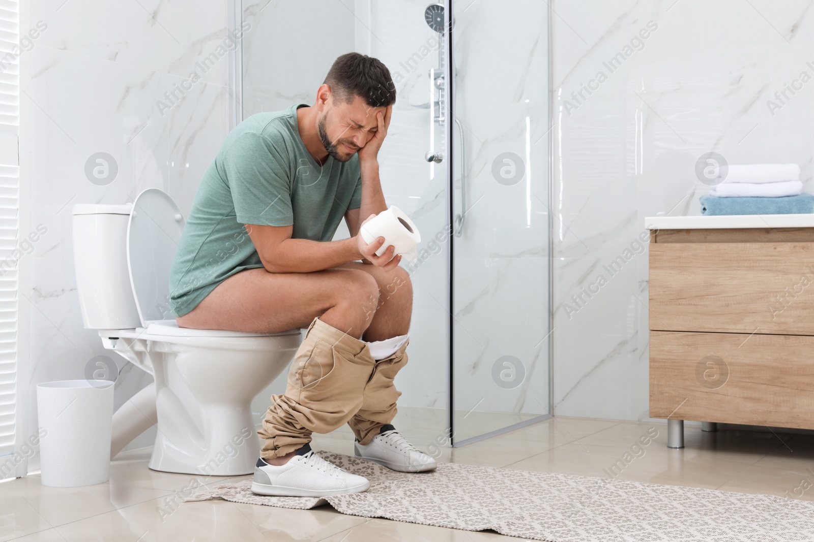 Photo of Man suffering from hemorrhoid on toilet bowl in rest room