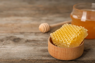 Photo of Tasty fresh honeycomb in bowl on wooden table