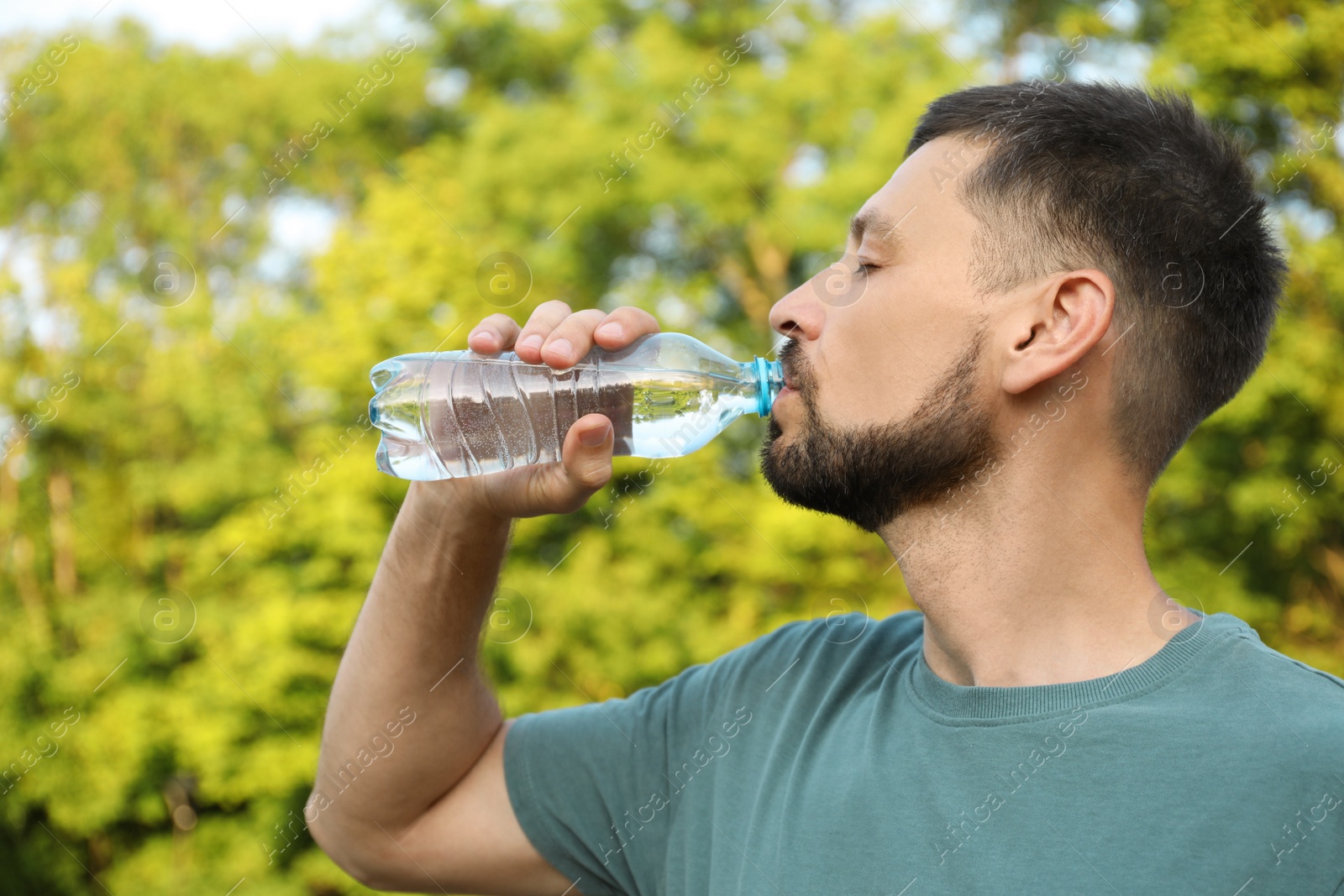 Photo of Man drinking water outdoors on hot summer day. Refreshing drink