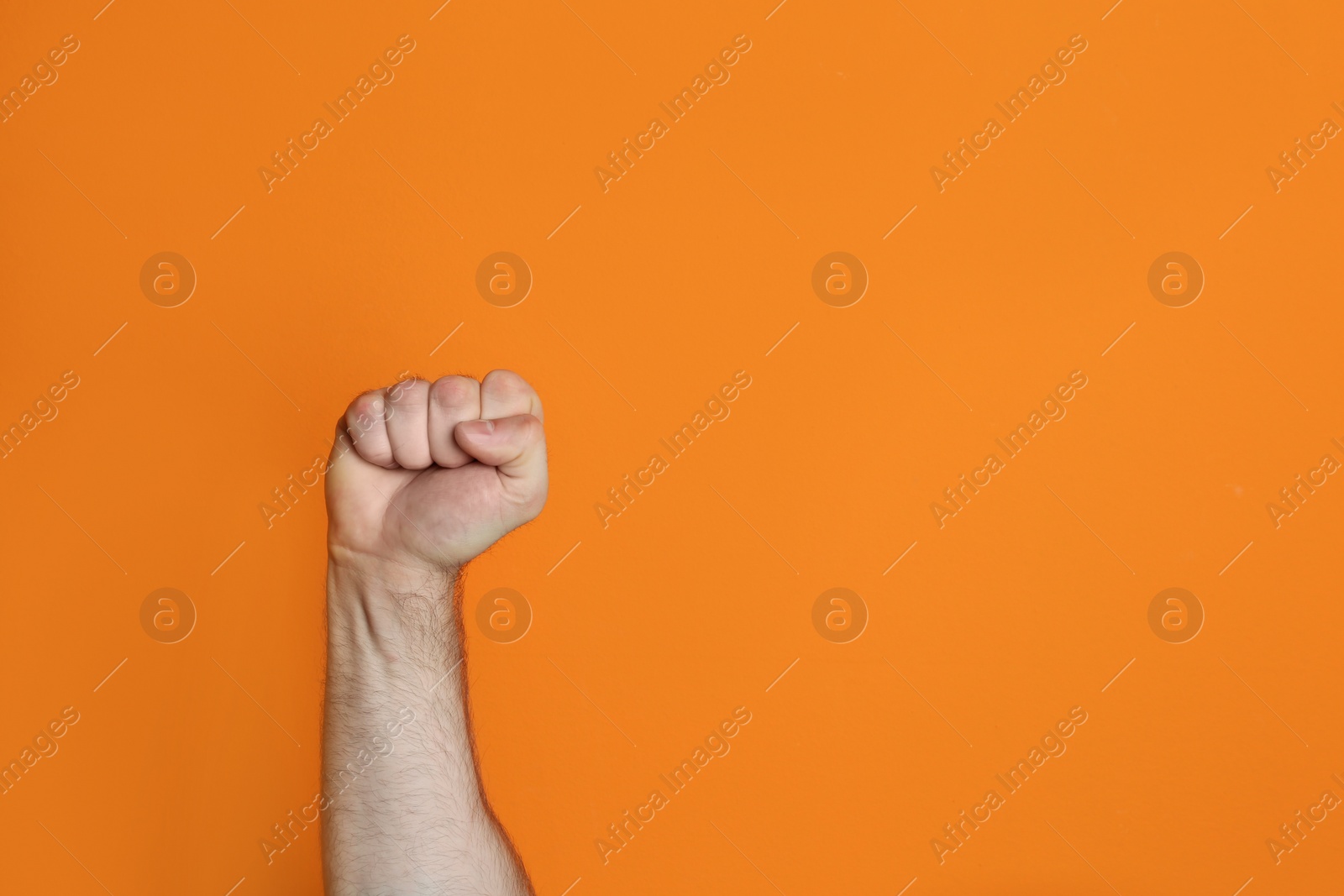 Photo of Young man showing clenched fist on color background. Space for text