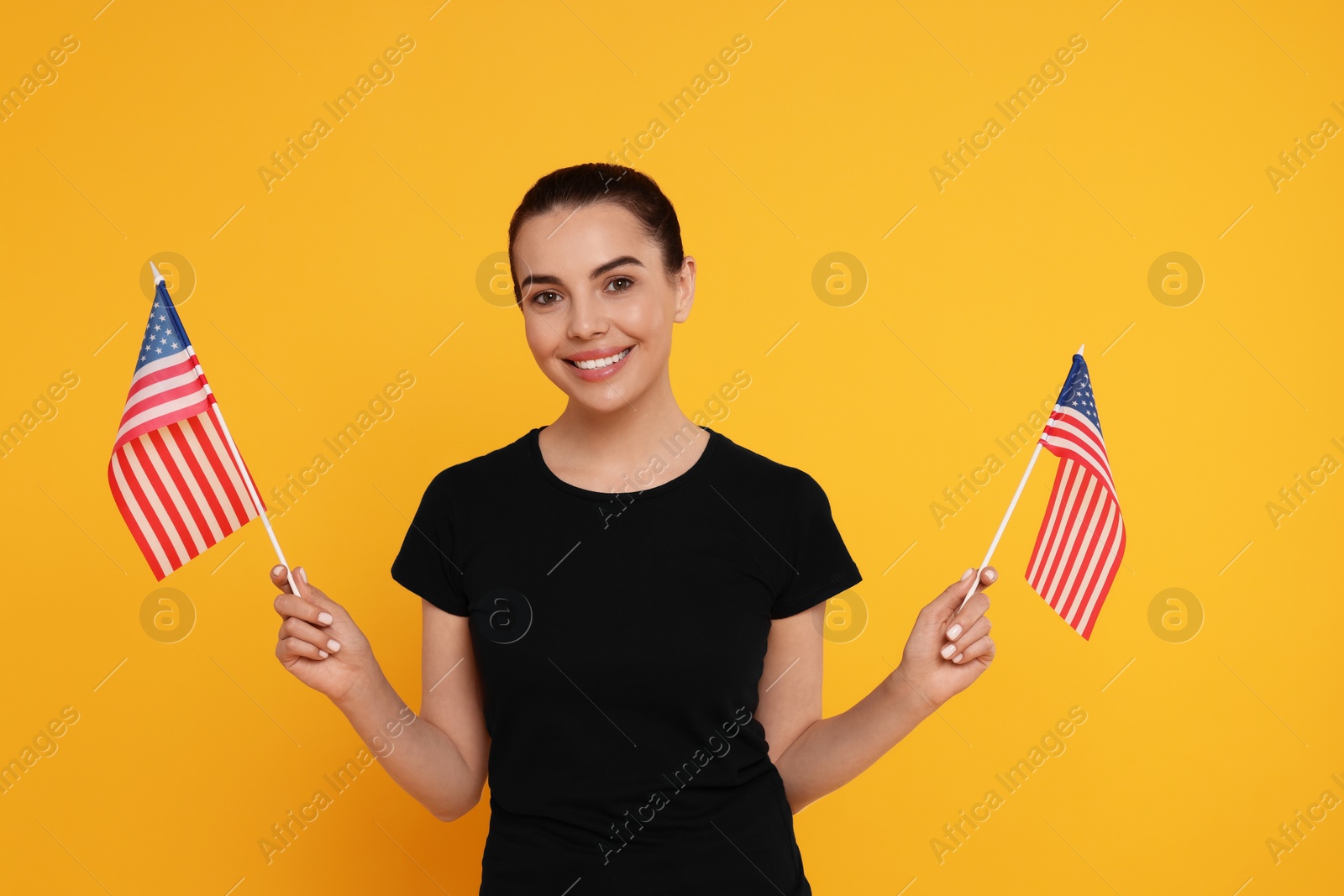 Photo of 4th of July - Independence Day of USA. Happy woman with American flags on yellow background