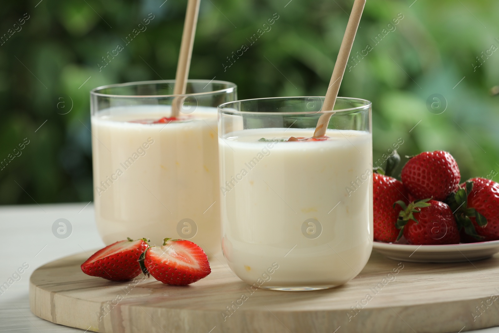 Photo of Tasty yogurt in glasses and strawberries on table outdoors, closeup