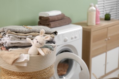 Laundry basket with baby clothes and toy in bathroom, closeup. Space for text