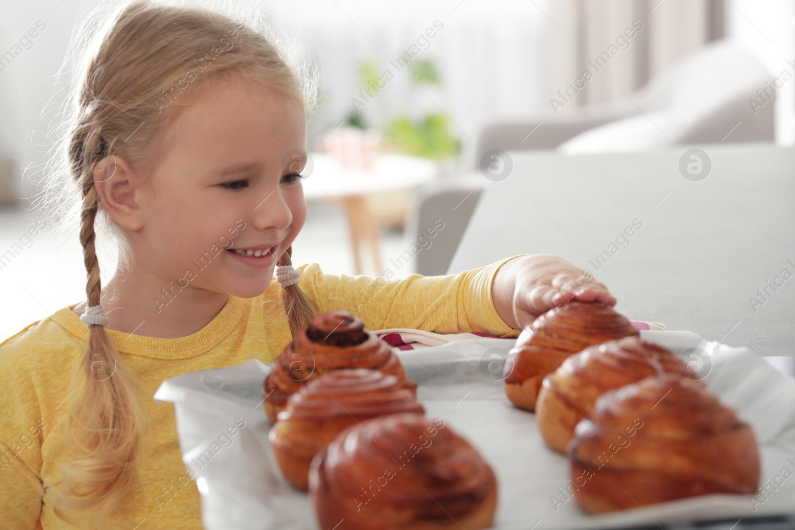 Photo of Little girl with tray of oven baked buns at home