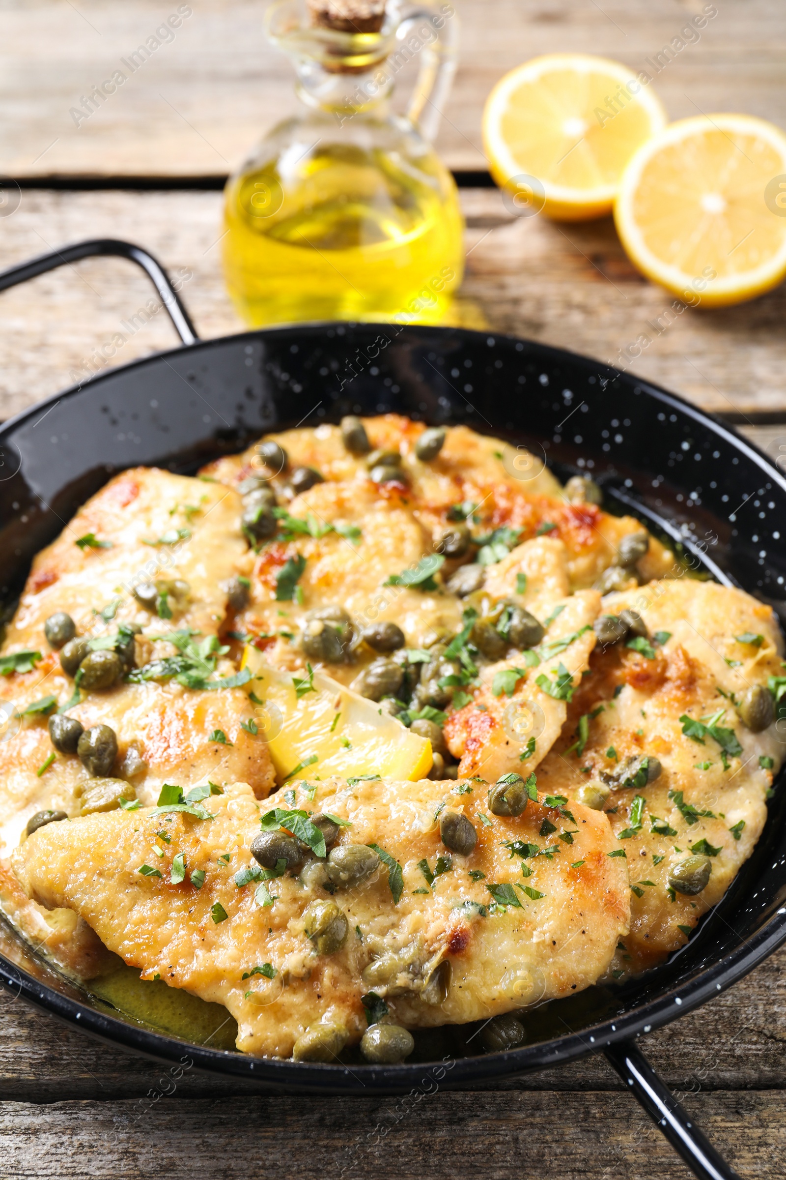 Photo of Delicious chicken piccata with herbs on wooden table