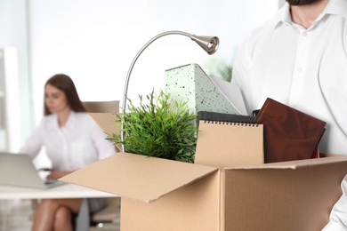 Young man carrying box with stuff in office, closeup