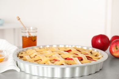 Photo of Raw traditional English apple pie in baking dish on light grey table, closeup