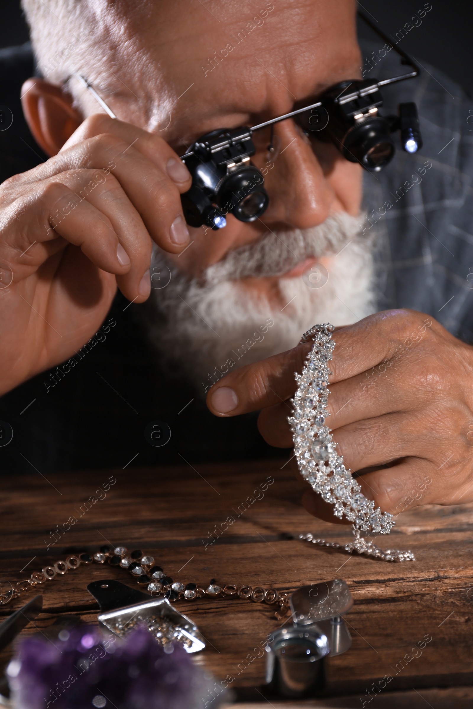 Photo of Male jeweler evaluating diamond necklace in workshop