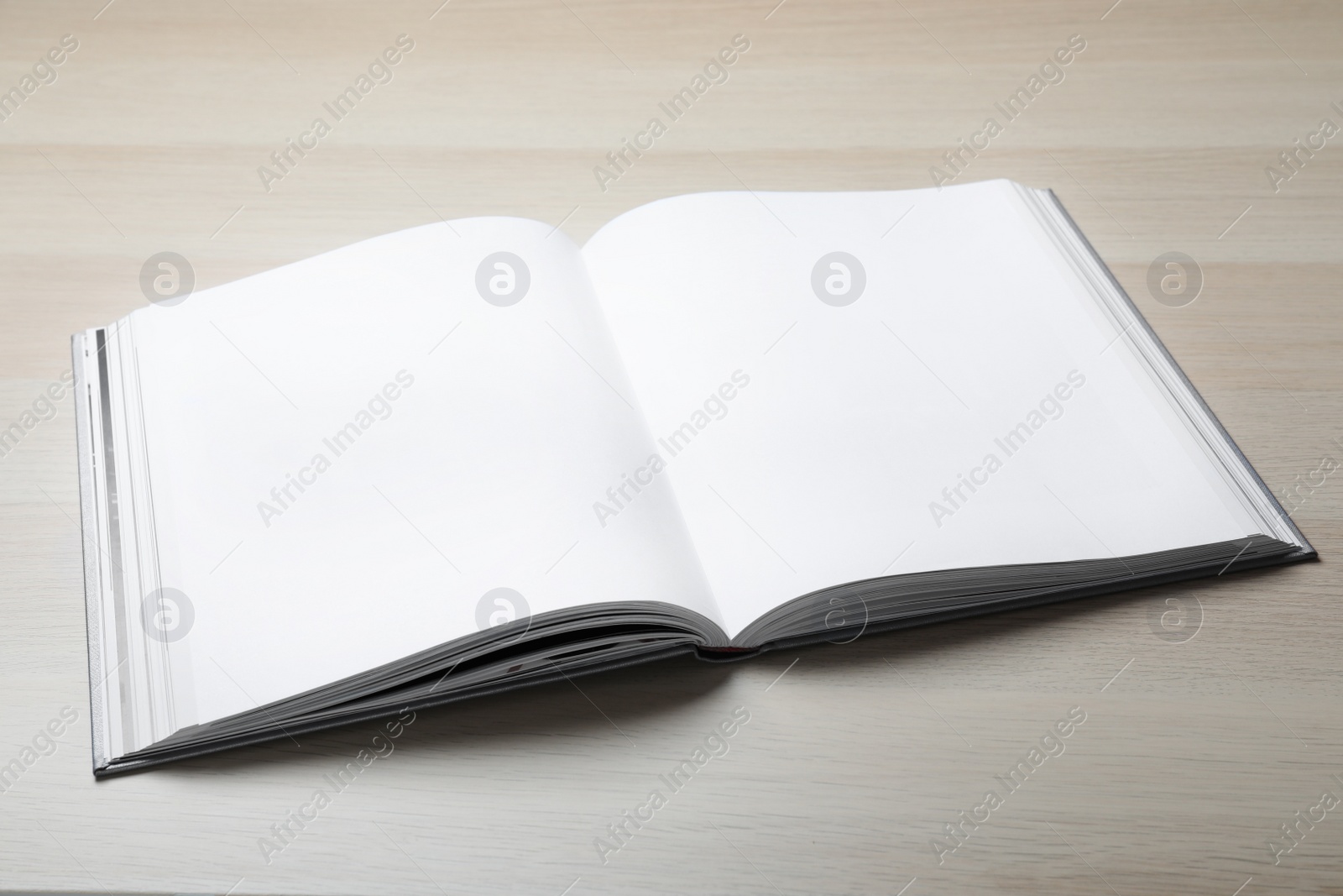 Photo of Open book with hard cover on wooden table