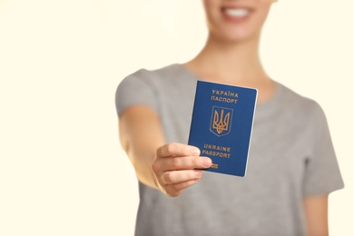 Woman holding Ukrainian travel passport against blurred background, closeup with space for text. International relationships