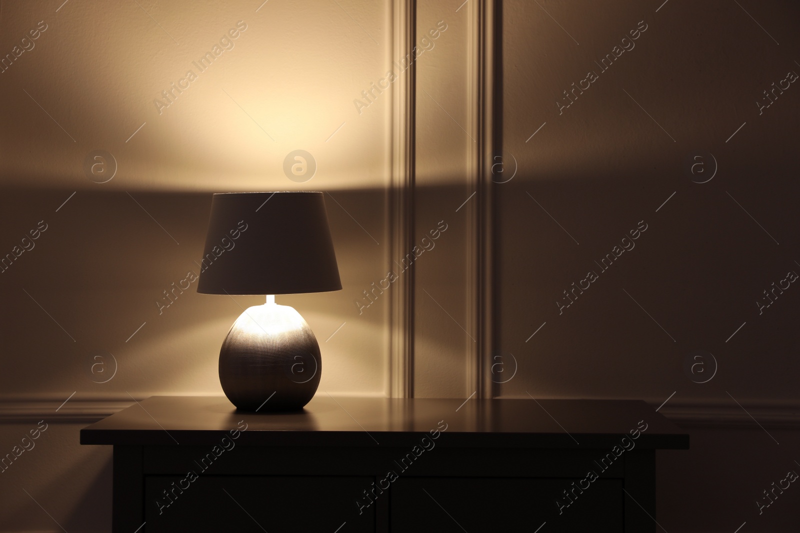 Photo of Stylish glowing night lamp on table in room. Space for text