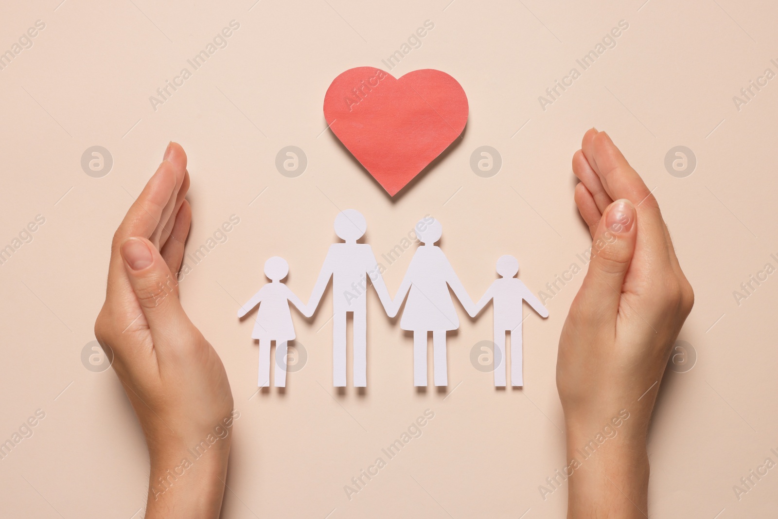 Photo of Woman protecting paper family figures and red heart on beige background, top view. Insurance concept