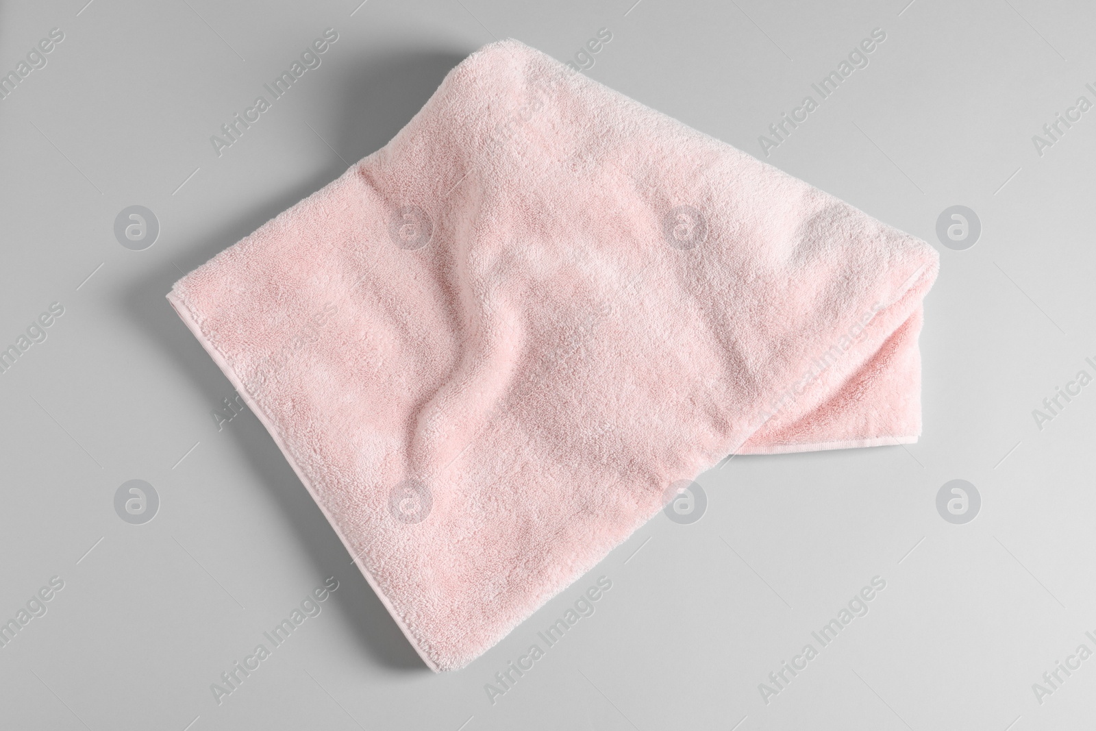 Photo of Soft folded towel on light background, top view