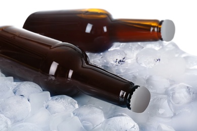 Photo of Bottles of beer on ice cubes against white background, closeup