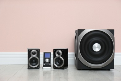 Modern powerful audio speaker system on floor near pink wall. Space for text