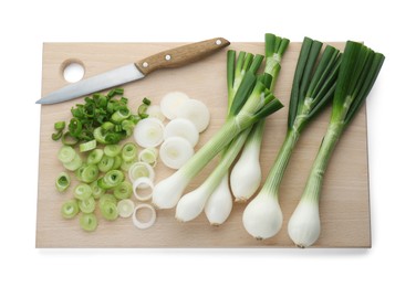 Photo of Wooden board with knife, whole and cut spring onions isolated on white, top view