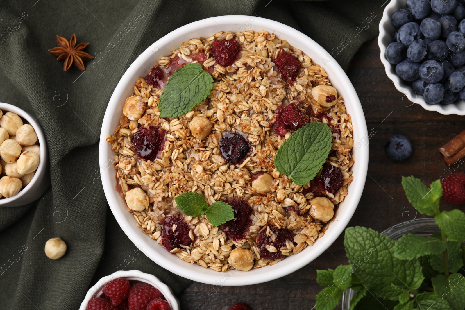 Photo of Tasty baked oatmeal with berries and nuts on wooden table, flat lay
