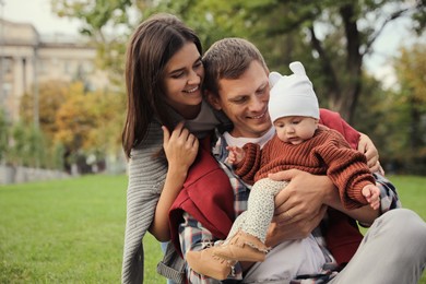 Happy parents with their adorable baby in park