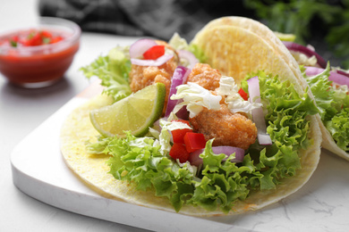 Photo of Delicious fish tacos served on light grey table, closeup