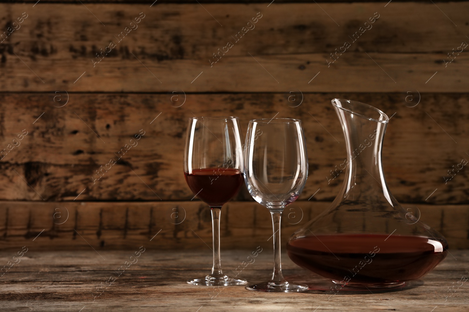 Photo of Elegant decanter with red wine and glasses on wooden table
