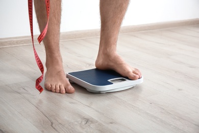 Overweight man measuring his weight indoors