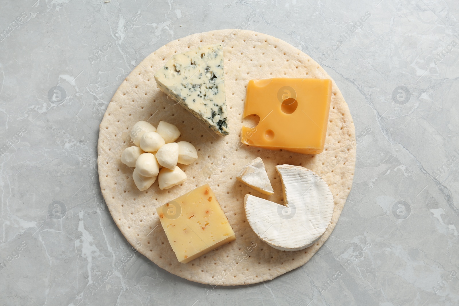 Photo of Pizza crust with fresh ingredients on marble table, top view