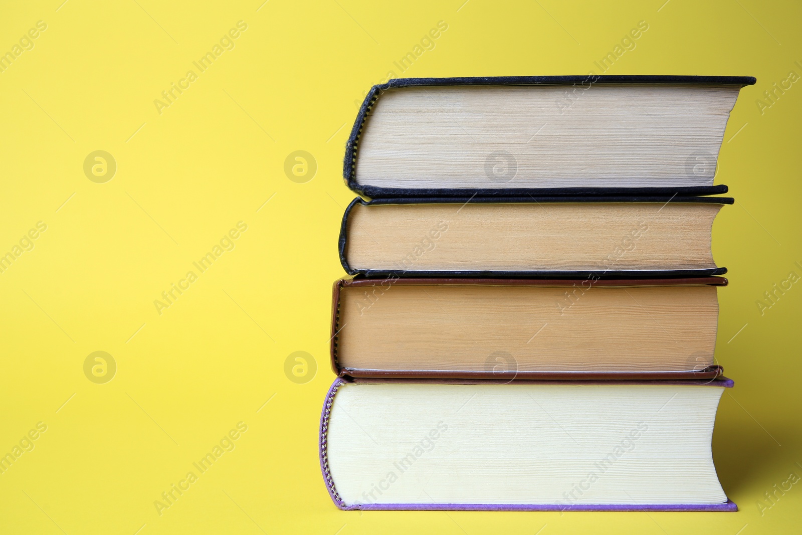 Photo of Collection of hardcover books on yellow background, space for text