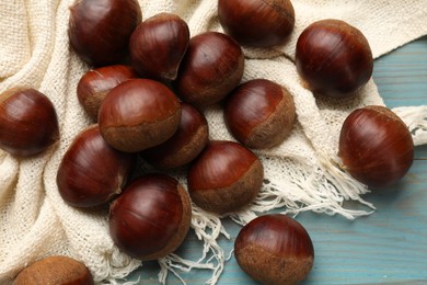 Photo of Roasted edible sweet chestnuts on light blue wooden table, flat lay