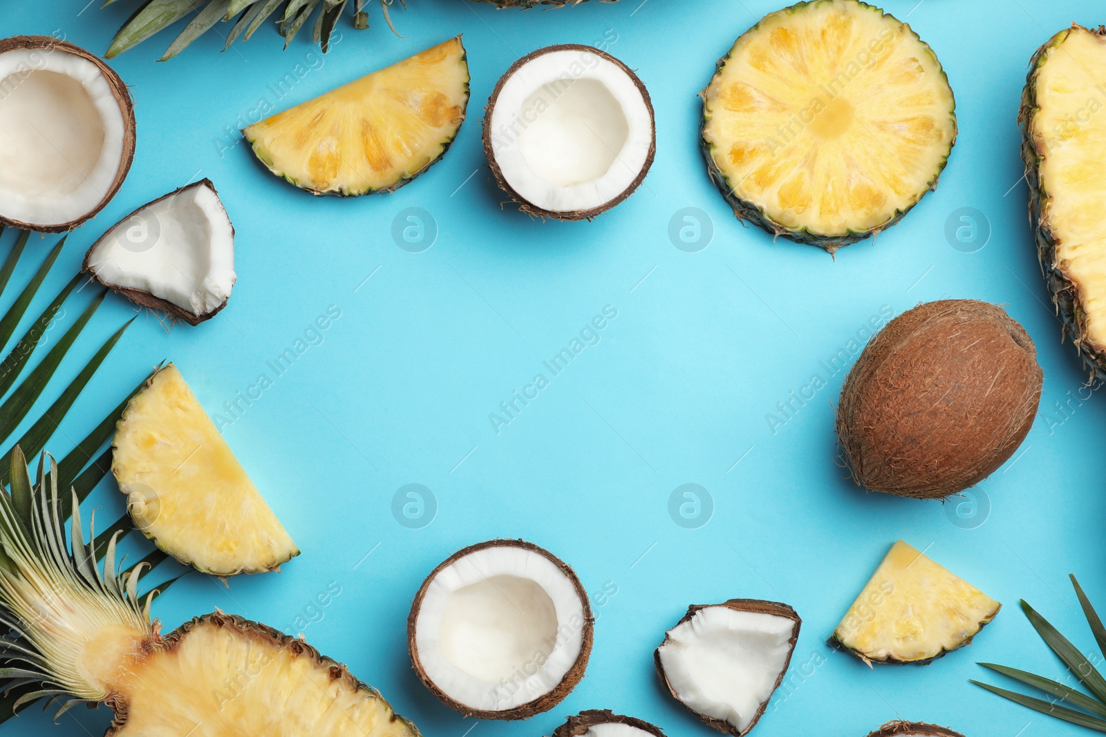 Photo of Frame made with coconut and pineapple on blue background, flat lay. Space for text