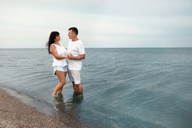 Photo of Happy mature couple spending time together on sea beach. Space for text