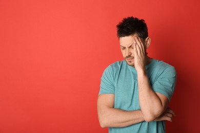 Photo of Man suffering from terrible migraine on red background. Space for text