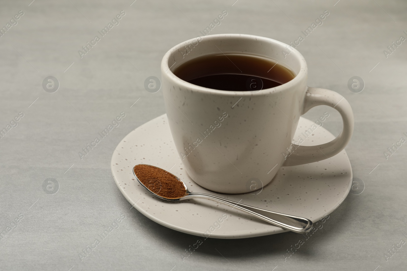 Photo of Cup of delicious chicory drink and spoon with powder on light grey table