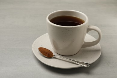 Cup of delicious chicory drink and spoon with powder on light grey table