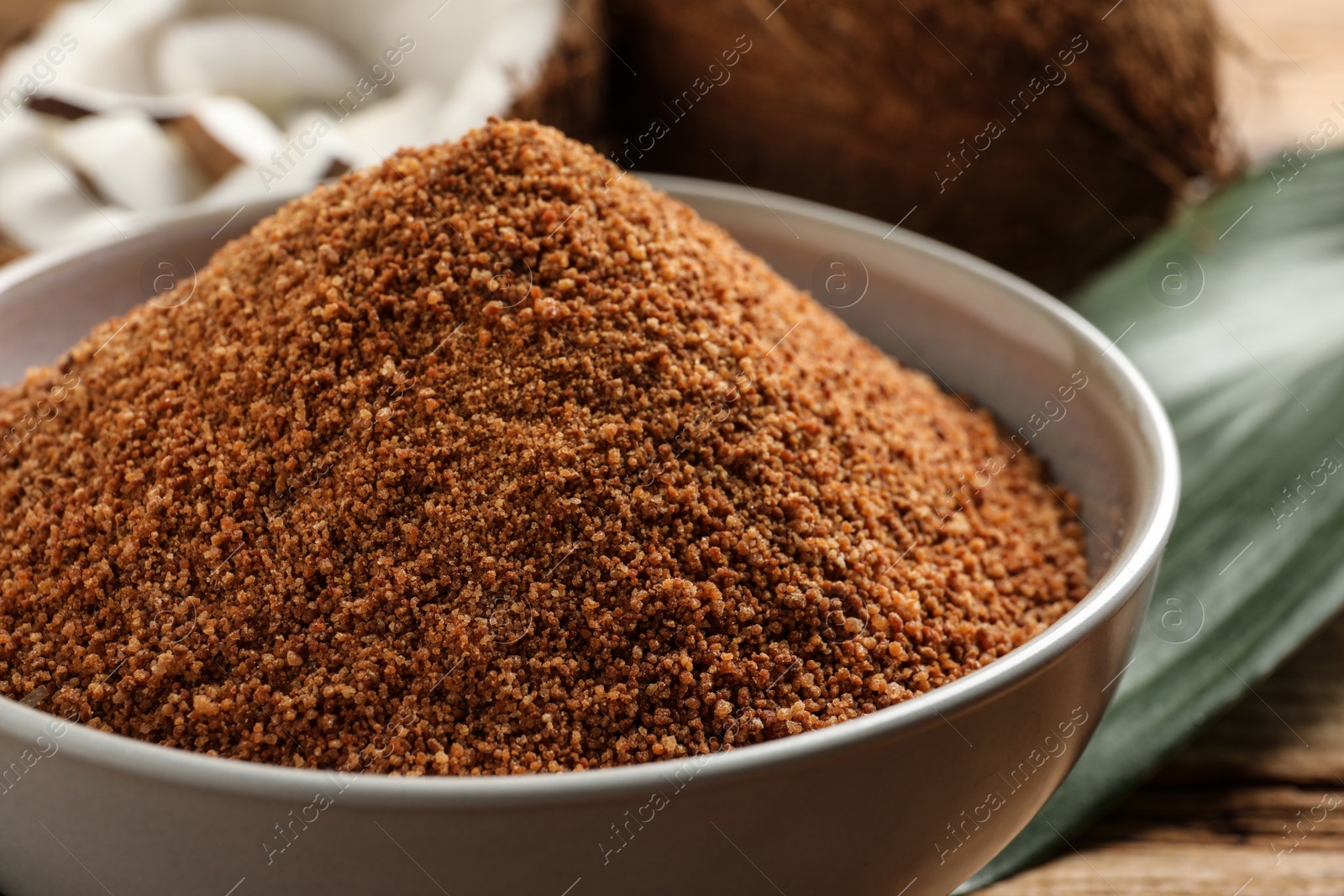 Photo of Natural coconut sugar in ceramic bowl on table, closeup