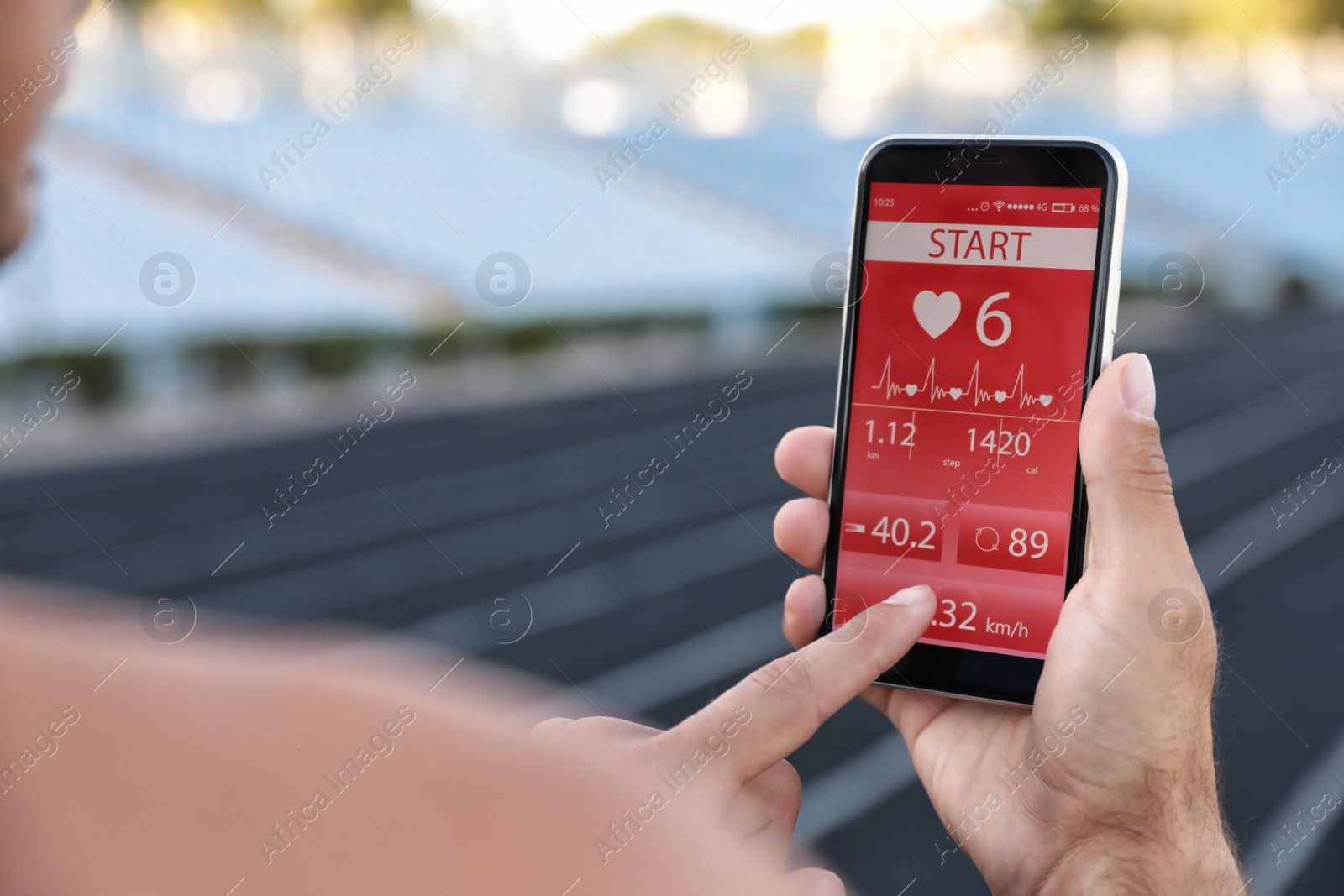 Photo of Man using fitness app on smartphone at stadium, closeup