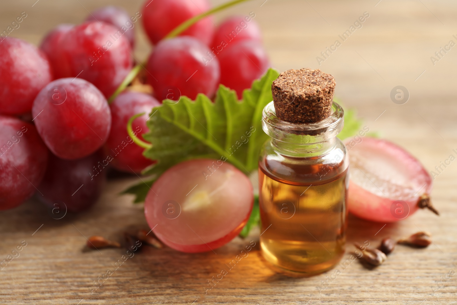 Photo of Bottle of natural grape seed oil on wooden table. Organic cosmetic