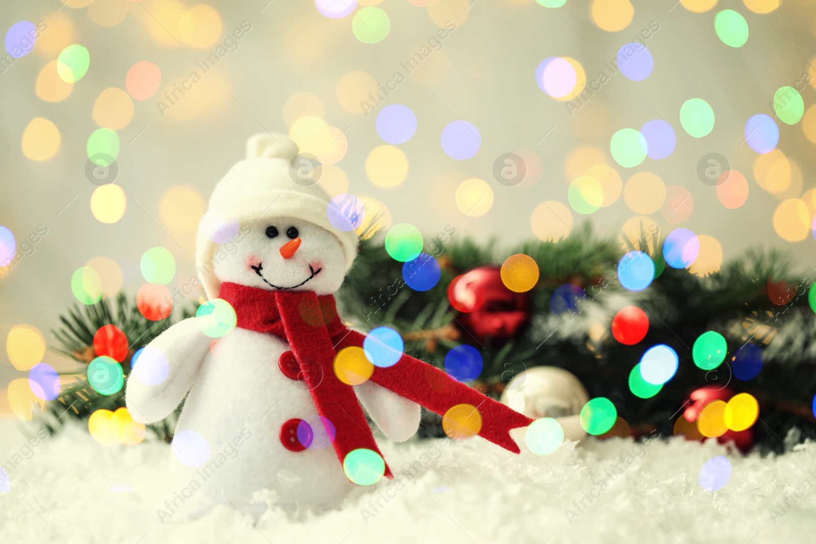 Image of Cute snowman and fir tree branches with Christmas balls on snow, bokeh effect. Space for text