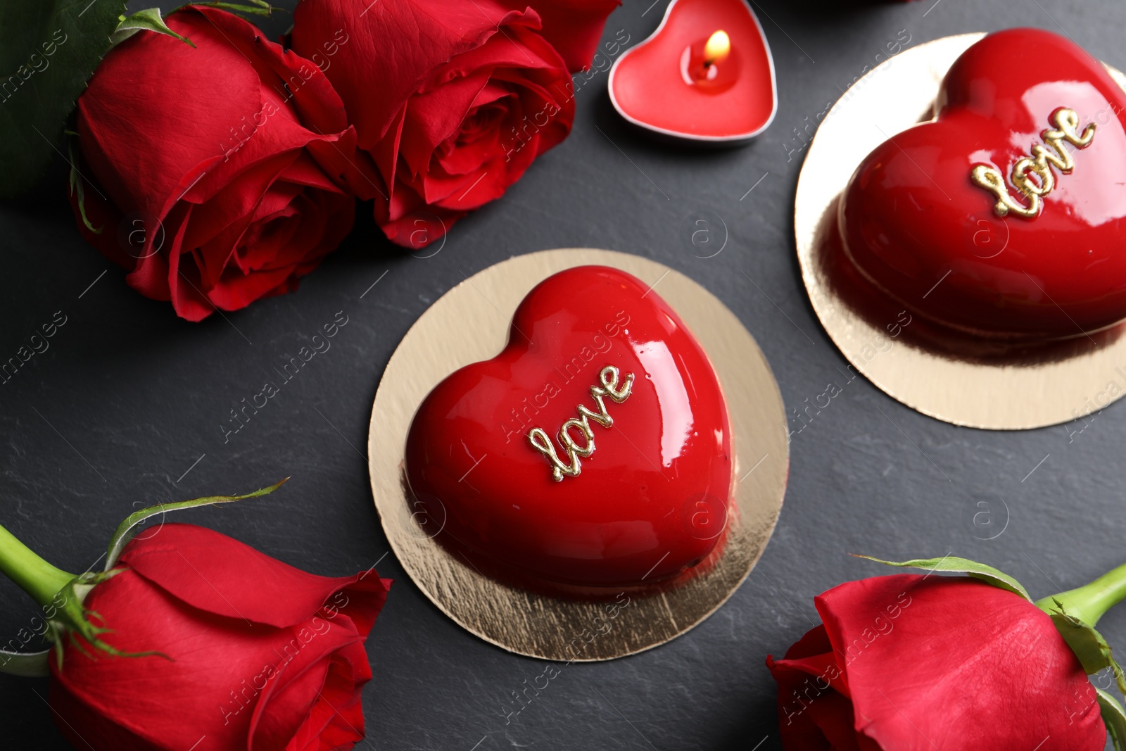 Photo of St. Valentine's Day. Delicious heart shaped cakes, roses and candle on black table, flat lay