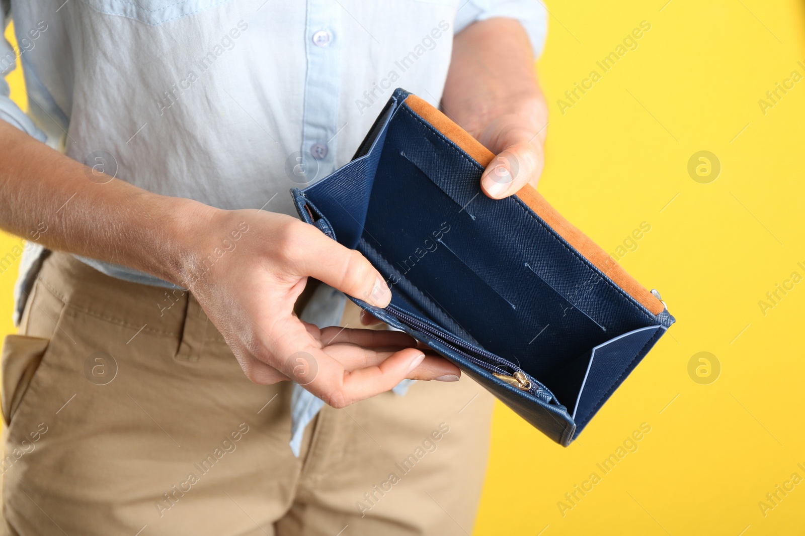 Photo of Woman showing empty wallet on yellow background, closeup