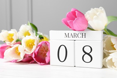 International Women's day - 8th of March. Wooden block calendar and beautiful flowers on white table